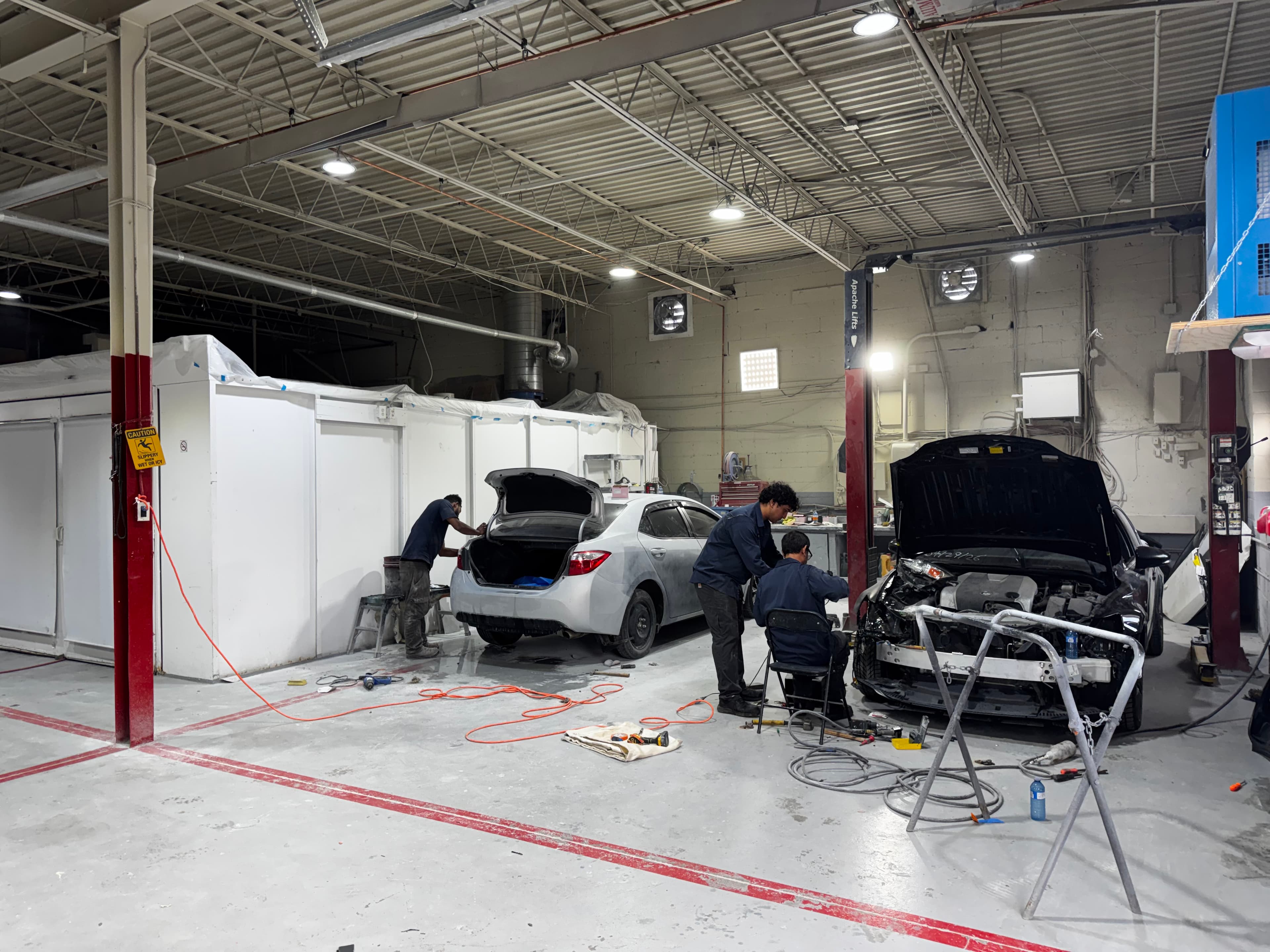 Two vehicles being repaired by technicians inside the Greensburg Auto service shop